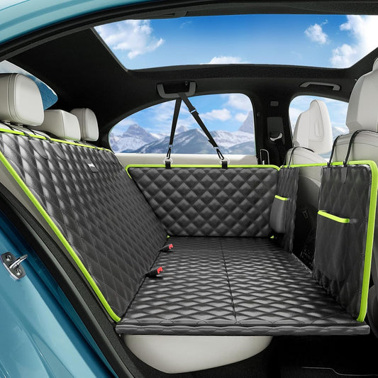 Black quilted dog car seat cover with neon green trim installed in blue vehicle rear seat with mountain view through window.