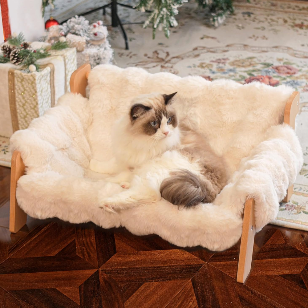 Cream and white cat lounging on an elevated wooden sofa bed with plush faux fur cushioning.