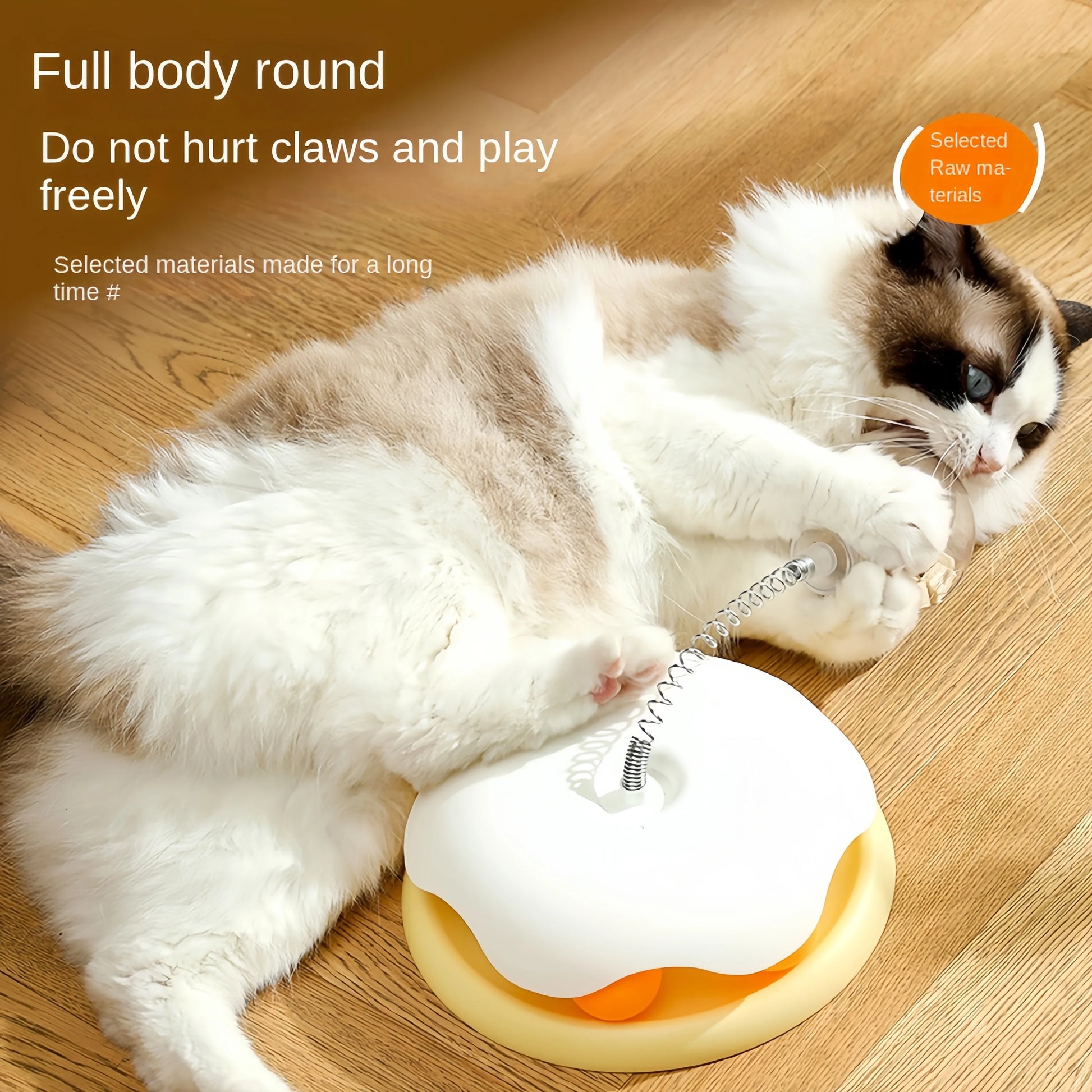 White and gray cat playing with white and orange interactive puzzle ball toy on wooden floor.